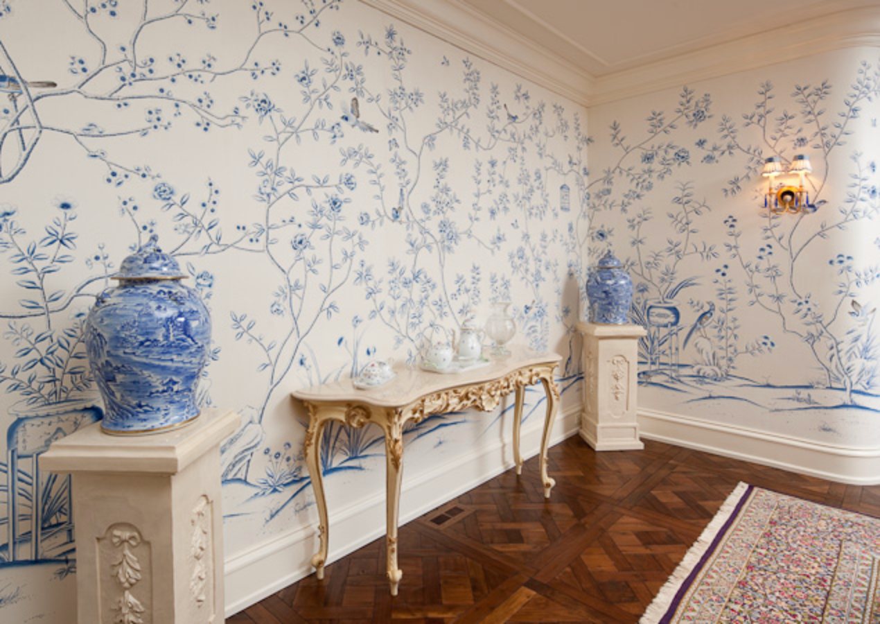 Foyer hung with a blue and white hand-painted chinoiserie mural, porcelain urns on plinths