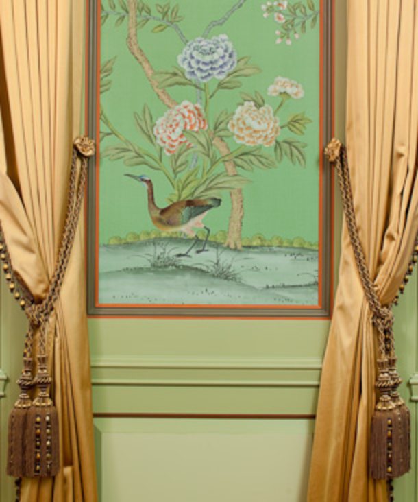 Framed green silk mural panel between gold silk drapery tie-backs