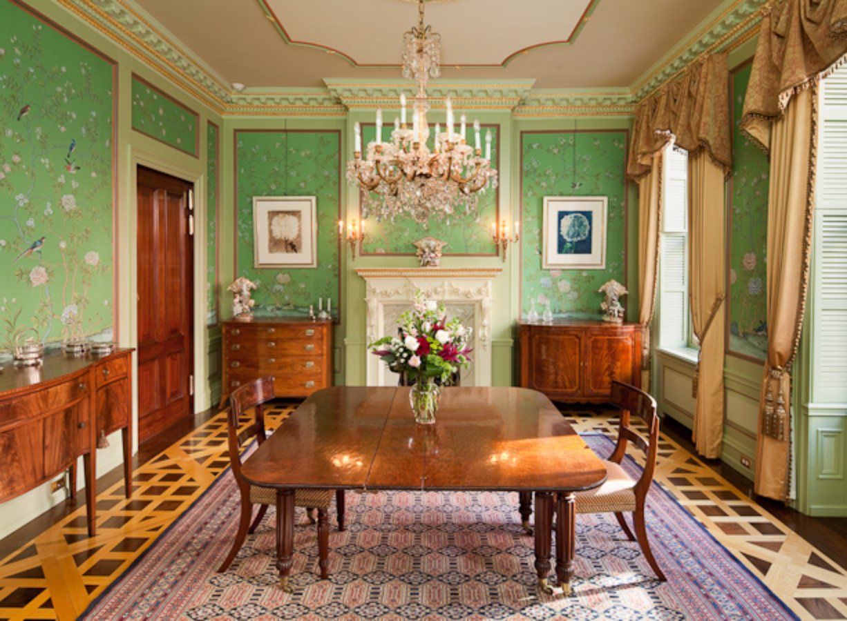 Green hand-painted silk mural panels framed in moulding around a dining room fireplace